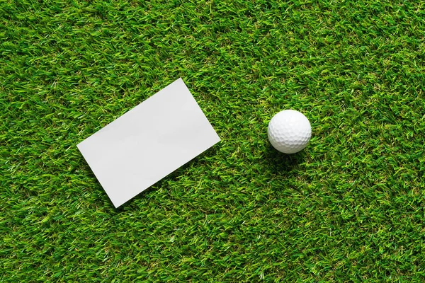 Fondo de papel blanco y pelota de golf en la hierba verde de la cancha de golf — Foto de Stock