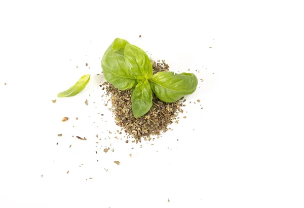 Foglie di basilico verde fresco su cumulo di basilico essiccato, su fondo bianco . — Foto Stock