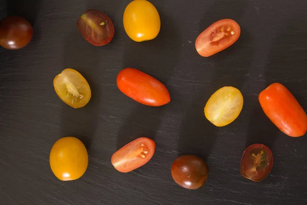 Bunte Kirschtomaten, auf schwarzem Hintergrund. — Stockfoto