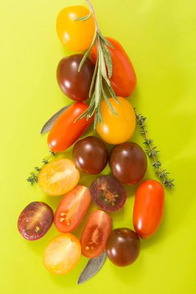 Conjunto de tomates cereja coloridos com ervas, em chartreuse fundo amarelo . — Fotografia de Stock