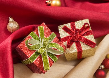 İki yay, kırmızı ve altın dalgalı saten kumaşlar Noel topları ile üzerine kutularıyla hediye.