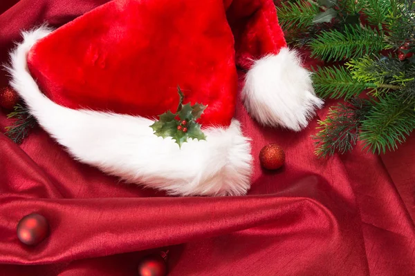 Капелюх Санти з різдвяними прикрасами, на червоній хвилястій тканині . — стокове фото