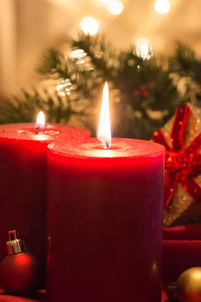 Candele rosse accese con palline di Natale, su tessuto rosso e sfondo dorato con bokeh . — Foto Stock