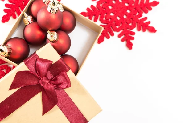 Scatola regalo di carta con fiocco rosso e palline di Natale, su sfondo bianco . — Foto Stock