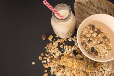 Kase kuru meyve ile müsli ve siyah arka plan üzerine bitki süt şişesi.