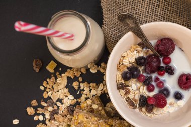 Kase müsli ile Dondurulmuş çilek ve siyah arka plan üzerine bitki süt şişesi.