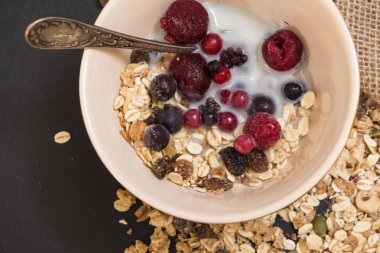 Kase Dondurulmuş çilek ve siyah arka plan üzerinde bitki süt ile müsli.