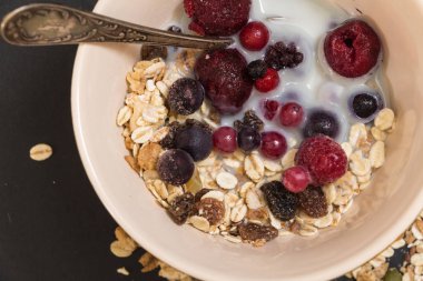 Kase Dondurulmuş çilek ve siyah arka plan üzerinde bitki süt ile müsli.