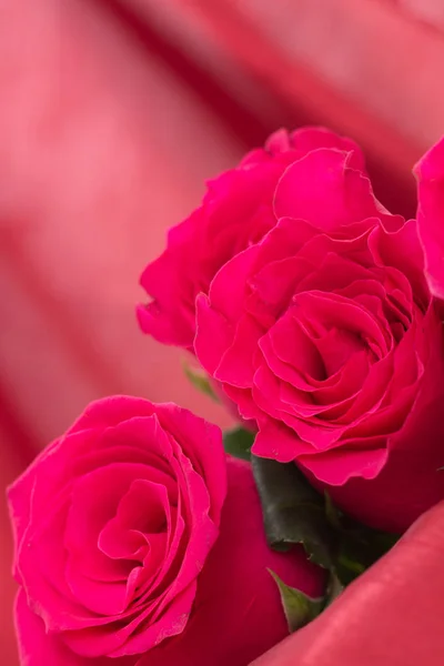 Крупный план букета красных роз с размытым фоном из красной ткани . — стоковое фото