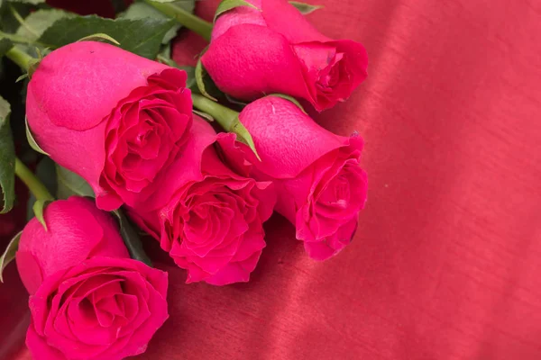 Крупный план букета красных роз на фоне красной ткани . — стоковое фото