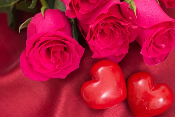 Primo piano di rosso due cuori e rose bouquet, su sfondo tessuto rosso . — Foto Stock