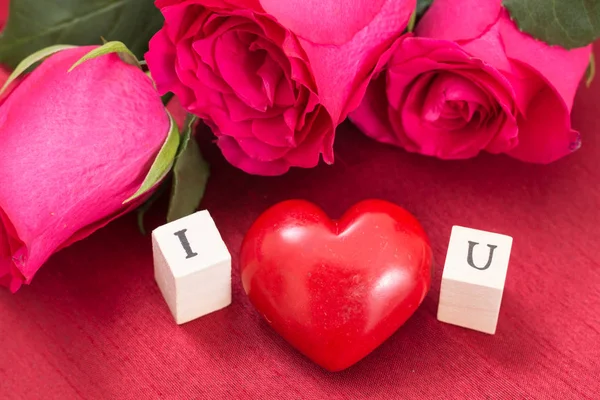 Coeur rouge et roses, et cubes en bois avec des lettres I et U. Je t'aime concept . — Photo