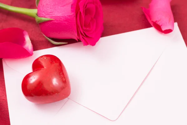 Coração vermelho com envelope rosa e rosa vermelha e pétalas close-up . — Fotografia de Stock