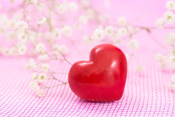 Kırmızı kalp ve beyaz çiçekler, pembe örgü kumaş üzerine closeup. — Stok fotoğraf