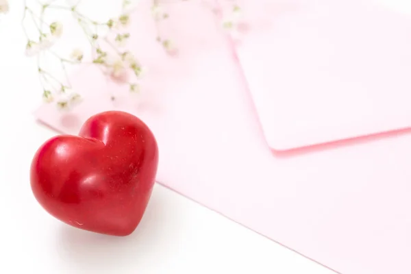 Närbild av ett rött hjärta med rosa kuvert och vita blommor. — Stockfoto