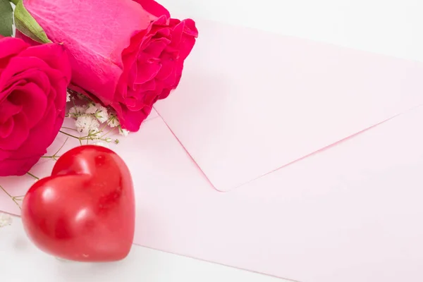 Červené srdce s růžovou obálku a červené růže closeup. — Stock fotografie