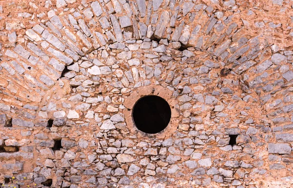 Kamenná zeď s kulatým oknem starobylé pevnosti. — Stock fotografie
