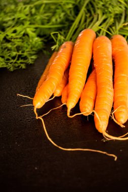 Yapraklarda siyah arka plan ile taze ıslak havuç