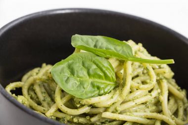 Spagetti makarna sosu pesto siyah kase, closeup arka plan ile.