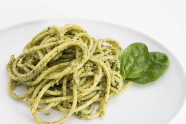 Spagetti makarna ile pesto sos beyaz tabak, closeup beyaz arka plan üzerinde.