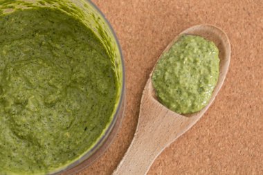 Taze yeşil pesto sos yapılmış kase ve tahta kaşık, closeup arka plan.