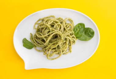 Canlı Sarı zemin üzerine bir sohbet kabarcık şeklinde beyaz tabak pesto soslu spagetti makarna.