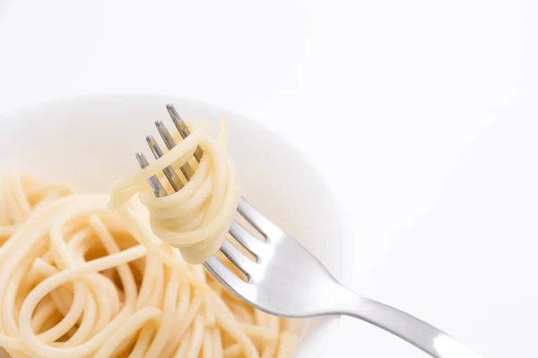 Massa de espaguete cozida lisa em tigela branca e em garfo, no fundo branco . — Fotografia de Stock