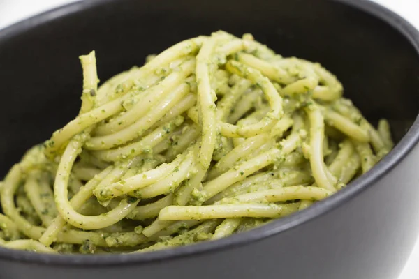 Spaghetti al pesto in ciotola nera, fondo primo piano . — Foto Stock