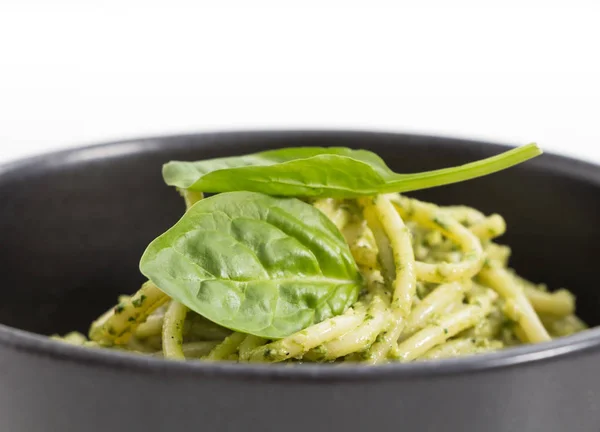 Massa de espaguete com molho pesto em tigela preta, fundo close-up . — Fotografia de Stock