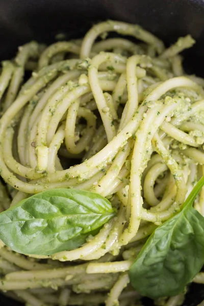 Spagetti makarna sosu pesto siyah kase, closeup arka plan ile. — Stok fotoğraf