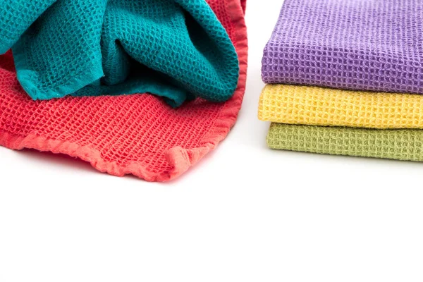 Pile of  messy and stack of folded colorful kitchen towels, on white background.
