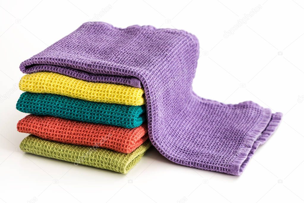 Stack of neatly folded colorful kitchen towels, on white background.