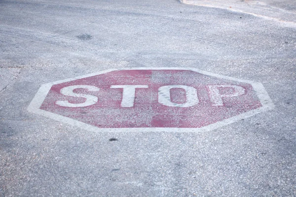 Verweerde rode zeshoek stopbord geschilderd op wegen bestrating oppervlak, close-up, achtergrond. — Stockfoto