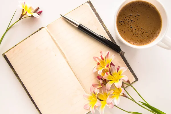 Kleurrijke Lentebloemen, met lege open dagboek voor tekst en kopje koffie op witte achtergrond. — Stockfoto