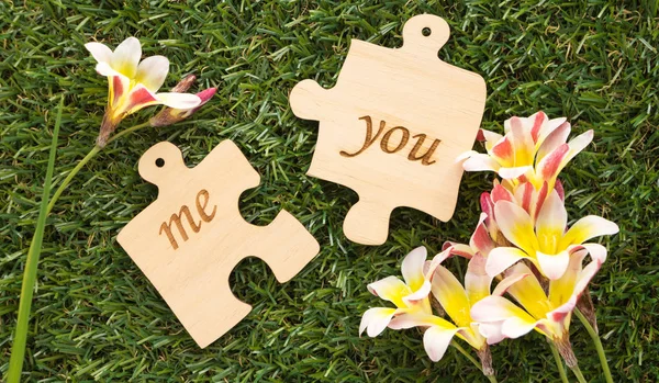 Zwei hölzerne Puzzleteile mit Wort ich und du, mit Blumen auf grünem Gras — Stockfoto