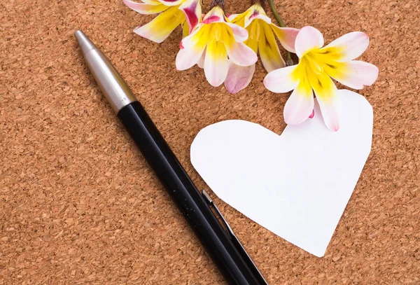 Blank note in shape of heart with copy-spce and flowers, on cork surface. — Stock Photo, Image