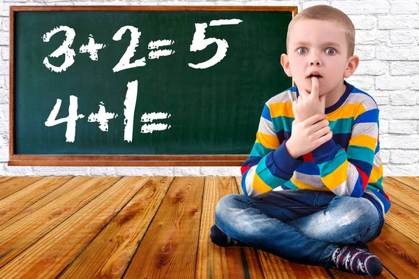 Babyjongen oplossen wiskunde voorbeelden. De student denkt en voelt in de buurt van de Board.Mathematical taken . — Stockfoto