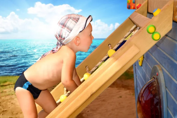 El niño sube la escalera en el parque infantil en la playa en el día soleado — Foto de Stock