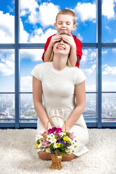 Unga vackra mamma med hennes son och en bukett blommor. Barnet stängt sin mors ögon, överraskning. Våren begreppet familjesemester. Kvinnodagen. — Stockfoto