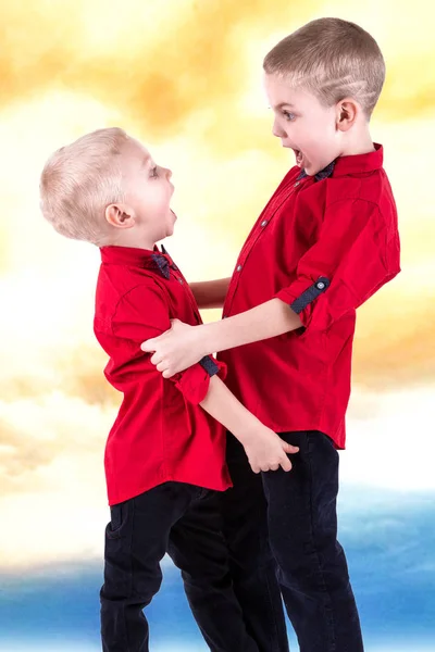 Two brothers play and have fun, spend time together.Children dressed in the same fashionable clothes, shirts . — стоковое фото