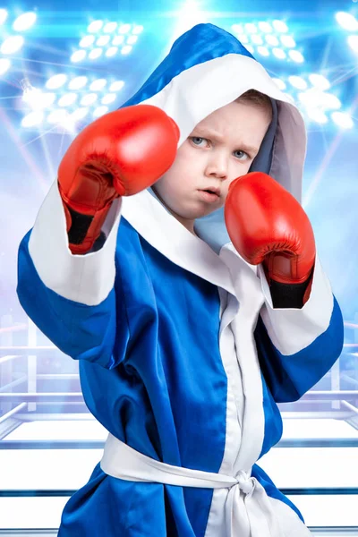 Kleine jongen boxer met rode handschoenen en kleed op de achtergrond van de ring. Kleine kampioen. De grote wint. — Stockfoto