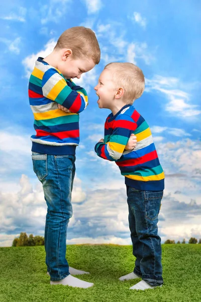 Dos hermanos juegan, se divierten, hacen amistades.Niños vestidos con la misma ropa . —  Fotos de Stock