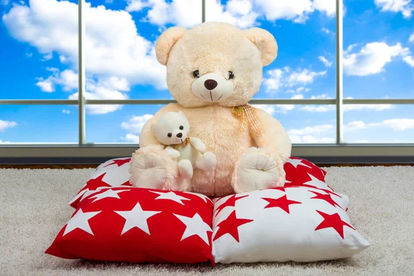 Soft Teddy bear with a heart.Soft beautiful decorative pillows for interior decoration in the house. sitting on the pillow on the background of the panoramic Windows. — Stock Photo, Image