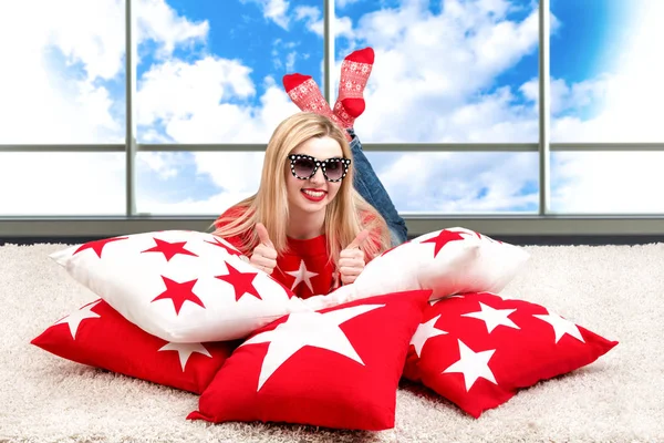 Hermosa joven rubia con gafas tumbadas en la almohada. Hermosas almohadas para decorar el interior de la casa. Almohada con adorno de estrella . — Foto de Stock