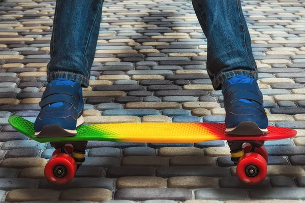 Un giovane skateboarder in scarpe da ginnastica e jeans, in piedi sul suo skate. Frammento primo piano dello skateboard e dei piedi . — Foto Stock