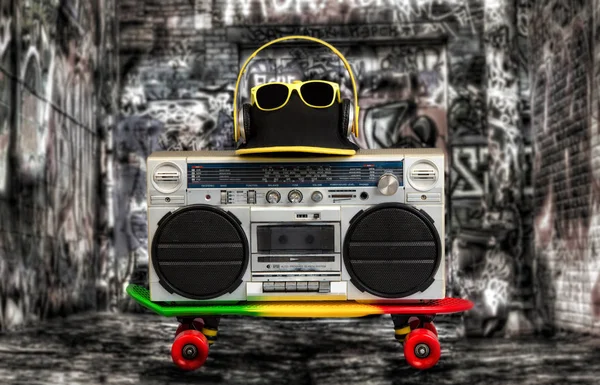 El concepto de estilo de música Hip Hop. Reproductor de audio vintage con auriculares. Skateboard, gorra de moda y gafas. Graffiti en las paredes . — Foto de Stock