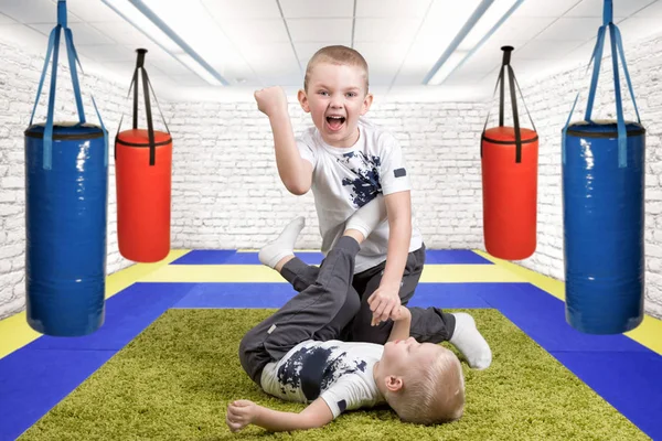 Twee broers spelen, plezier hebben, vrienden te maken. Jongens worstelen, sporten in de sportschool. Succes, emoties, genieten van de overwinning. — Stockfoto