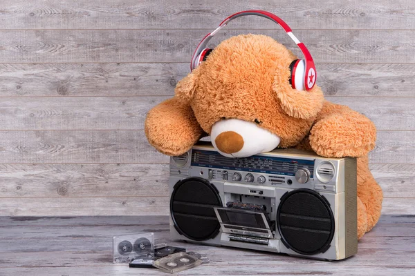 Oso de peluche con auriculares escuchando música en el reproductor de cassette de radio retro. Estilo vintage  . — Foto de Stock