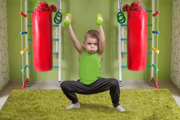Küçük bir çocuk bir egzersiz dumbbells ile gerçekleştirir. Çocuk dumbbells ile ağız kavgası. Spor, sağlıklı yaşam tarzı.