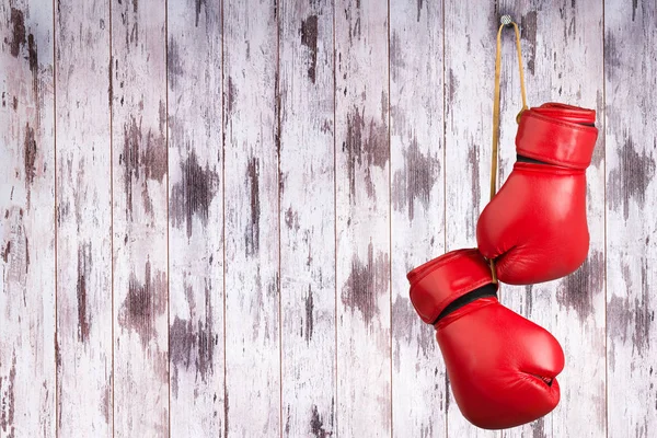 Paar rode lederen bokshandschoenen opknoping op een spijker op een houten muur. — Stockfoto